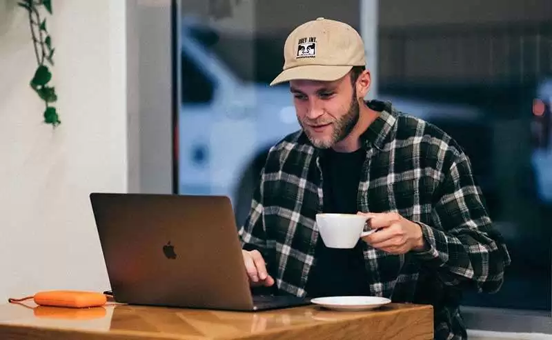 Klient mit Kaffee in der Hand vor dem Laptop im Life Coaching Call